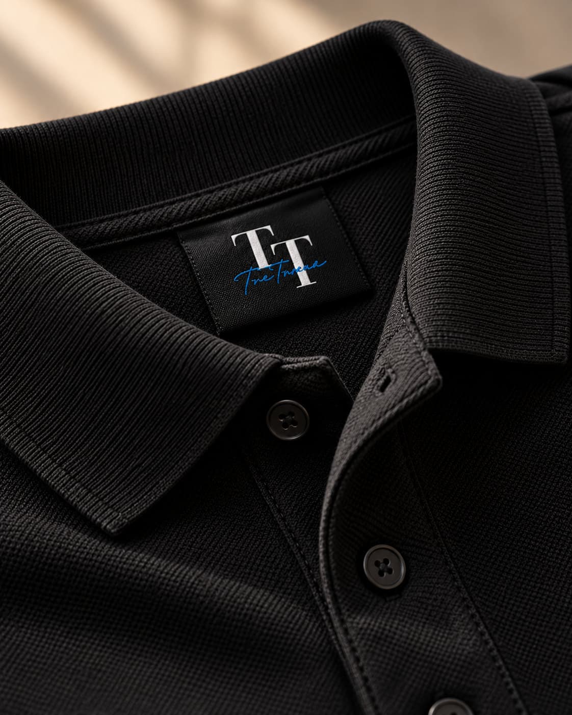 Close-up of a black polo collar, placket buttons and woven TreTrove neck label
