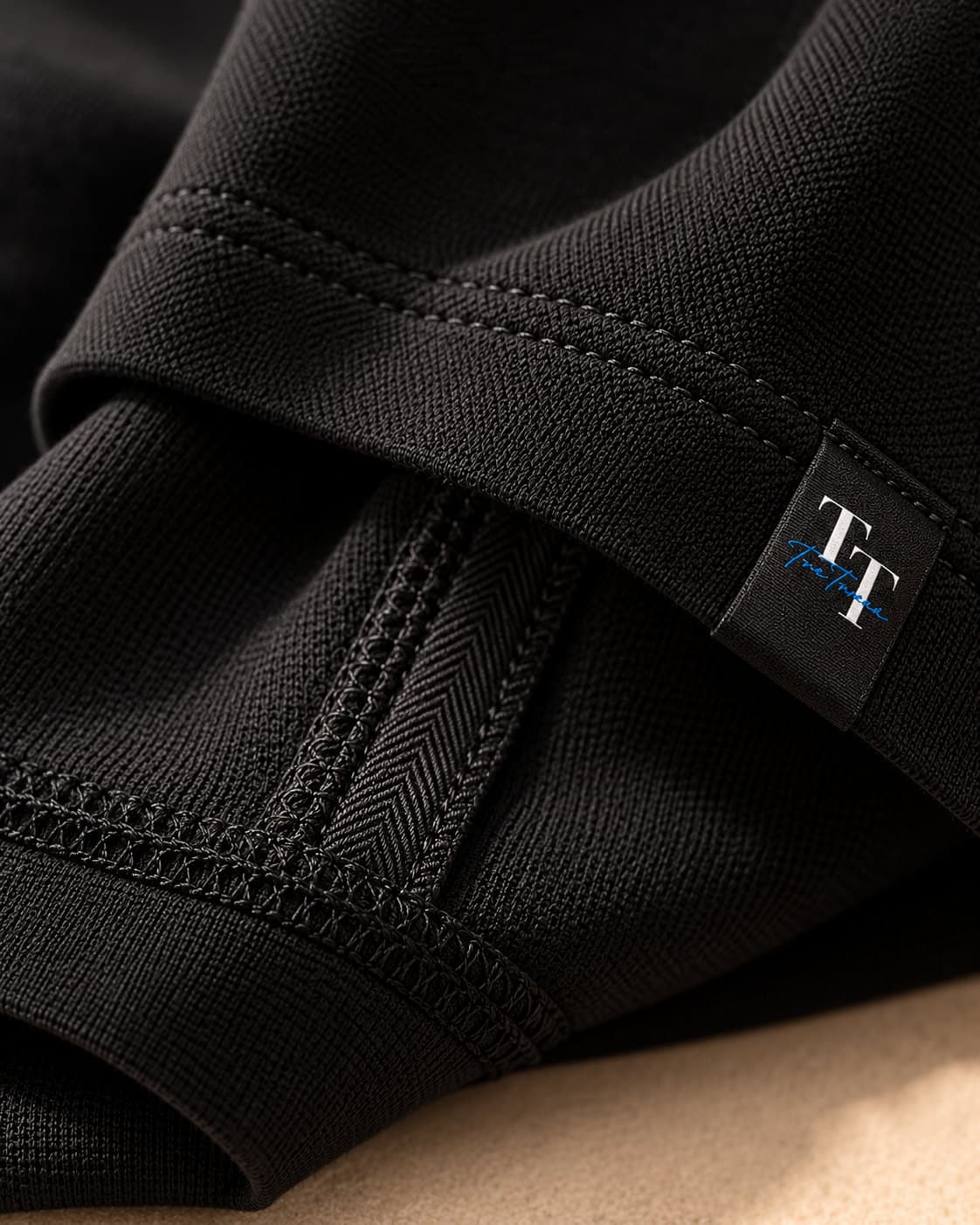 Close-up of a black sleeve hem with visible stitching and a woven TreTrove tab label